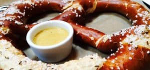 Close up of soft pretzel with salt and mustard dipping sauce
