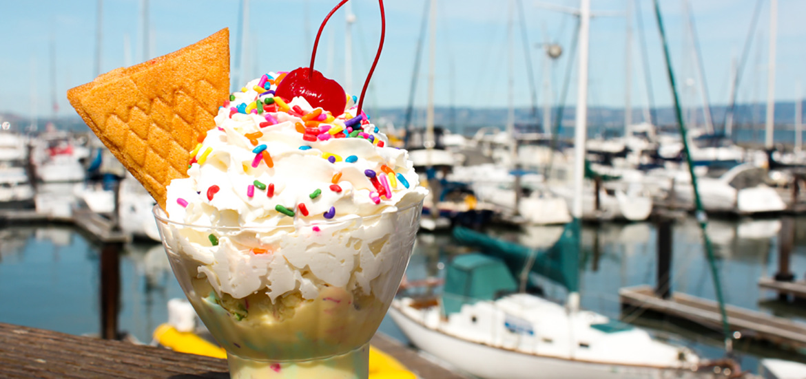 Ice cream sundae with a cherry in front of boats and water in Marina