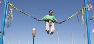 Boy in green shirt bouncing on bungee ride